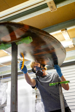 Shaper glassing surfboard underside in Australia