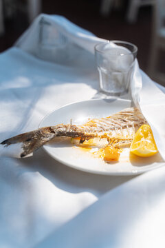 Fish bones and lemon on white plate