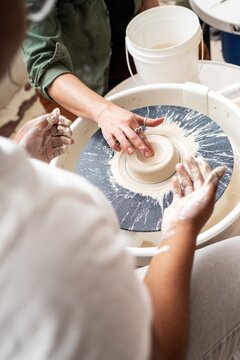 Instructor guiding student at pottery wheel