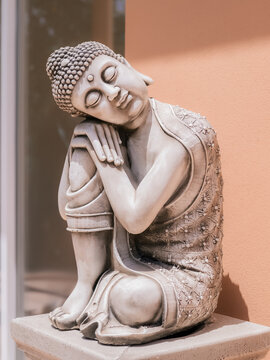 Buddha Statue Rests Against Orange Wall in Quiet Space