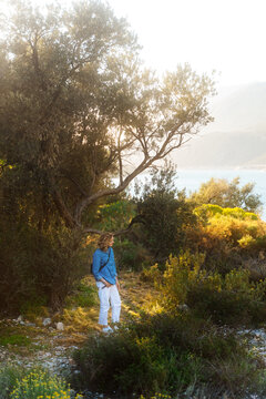 Woman standing on forest path near sea
