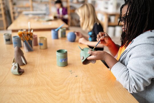 Students painting clay sculptures in art class