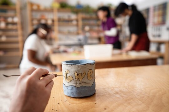 Child Carving Letters into Clay Mug in Art Class