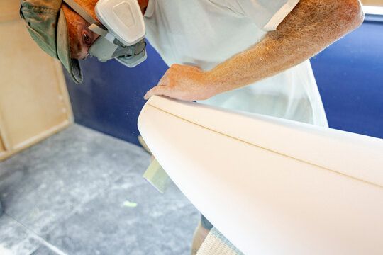Surfboard shaper refining asymmetrical tail 