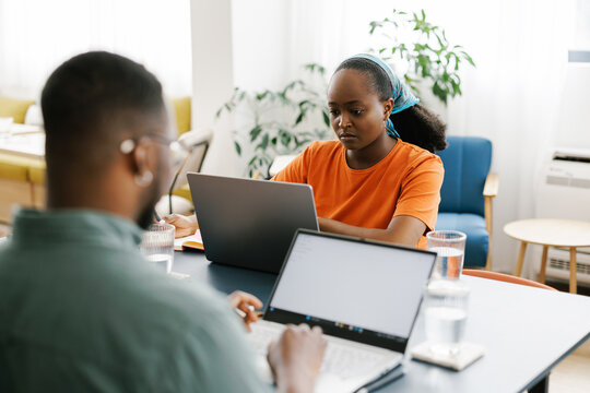 Two Young Black People Working on Laptops in a Modern Office Space