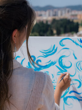 Woman painting on canvas at sunny terrace 