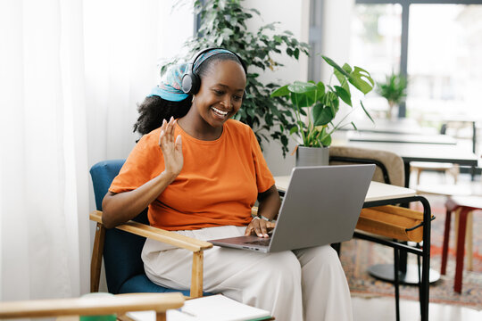 Woman Waves During a Video Call in a Bright Indoor Space