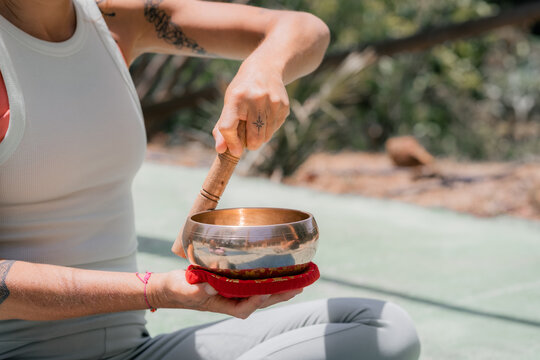 Woman Plays Singing Bowl Outdoors During Sunny Day