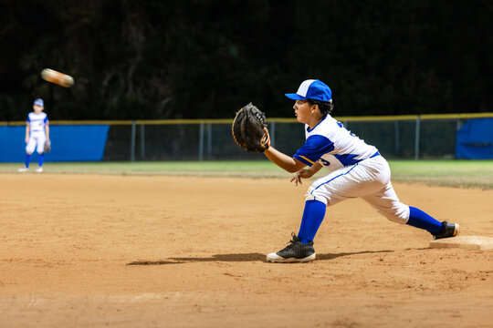 Young Player Catches Ball During Night Baseball Game