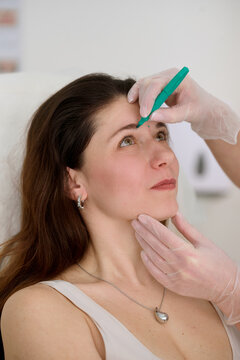 Cosmetologist marking woman&rsquo;s forehead before aesthetic procedure