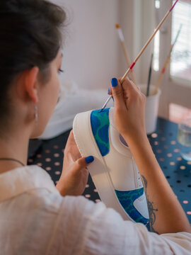 Woman Painting Colorful Design on Sports Shoe in Bright Room