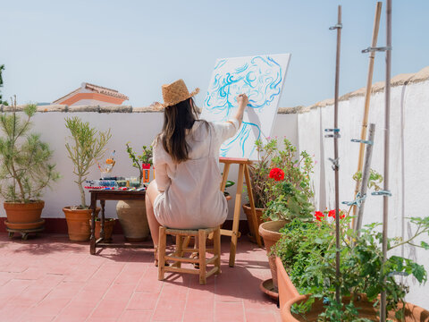 Woman Paints on a Canvas at Terrace on a Sunny Day