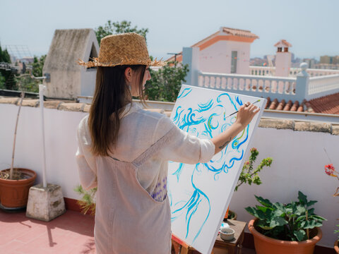 Woman painting at sunny rooftop 