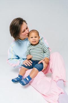 A mother sits with a small child in a bright studio.