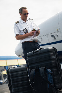 Pilot Checking Documents Beside Aircraft and Luggage