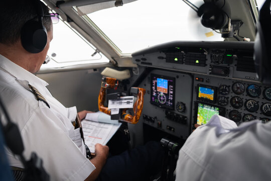 Pilots Reviewing Checklist Inside Aircraft Cockpit