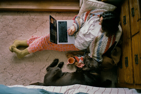 Woman sitting on a floor with the dog and working with laptop 