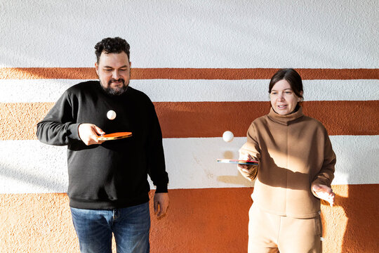 A man and a woman are training with rackets and balls.
