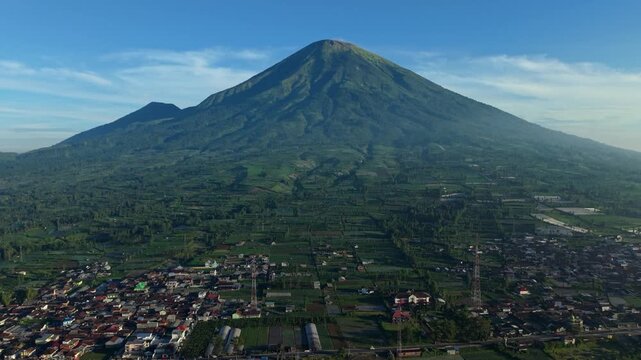 Aerial view of Mount Sindoro rising above the agricultural fields and village of Garung in Kecamatan Kalikajar, Jawa Tengah, Indonesia.