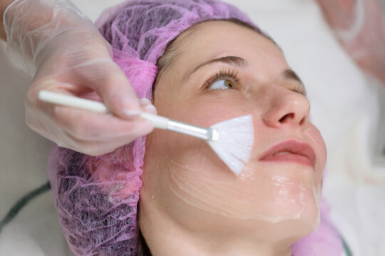 Cosmetologist applying facial mask in beauty clinic