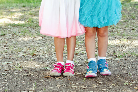 Two girls stand together in cute shoes