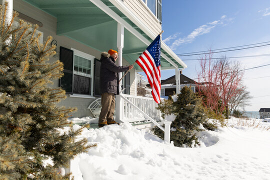 Portrait senior man American Flag porch snow house