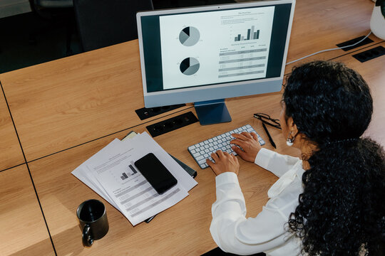 Businesswoman Analyzing Financial Charts on Computer at Desk
