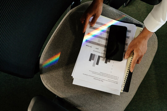 Smartphone Placed on Financial Reports with Rainbow Light Reflection