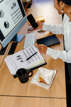 Businesswoman Checking Smartphone During Work Lunch at Desk
