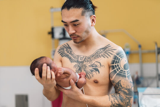Father holding newborn baby skin to skin hospital