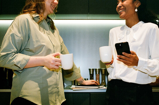 Business Colleagues Talking with Coffee Mugs in Office Kitchen