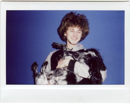 Young Man with Curly Hair Holding Spaniel Dog