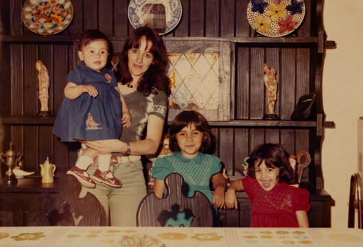 Mother holding baby with two older sisters from 1970s