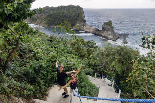 Two women posing on stairs above coast at Pantai Atuh, Bali