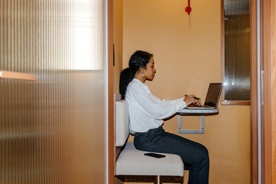 Businesswoman Working on Laptop in Private Office Booth