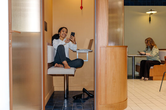 Businesswoman Using Smartphone in Office Privacy Booth