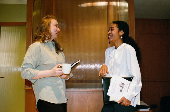 Two Businesswomen Chatting with Coffee in Office Interior
