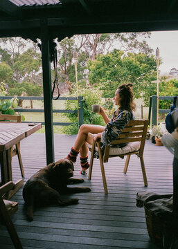 Woman with a cup of coffee sits on a deck 