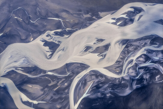 Abstract aerial of glacial river channels on dark volcanic plain