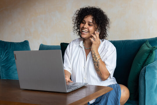 smiling woman talking on the phone, looking at laptop computer