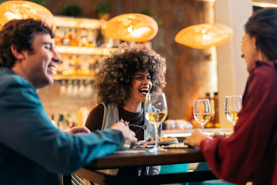 Friends laughing together enjoying dinner in restaurant