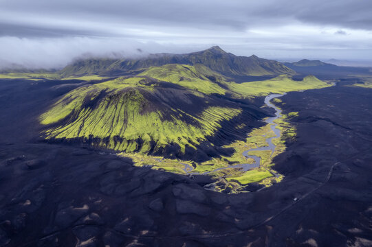 Moss-covered volcanic cone above black lava plain, Iceland