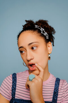 Thoughtful woman in pink striped shirt and denim overalls 