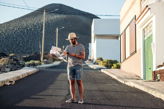 Young man traveling holding map and smartphone in Lanzarote