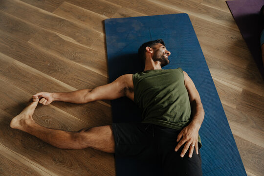 Man Stretches on Yoga Mat in Studio During Workout Session