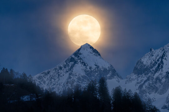 Full moon rising over snowy alpine peak, Switzerland
