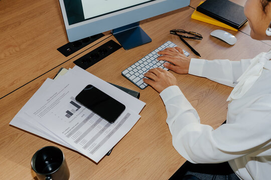 Businesswoman Typing on Keyboard at Office Desk With Documents