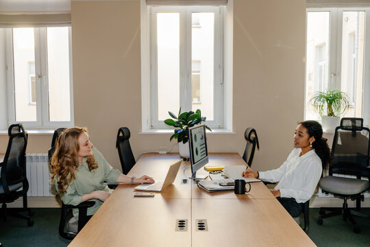 Two Colleagues Working Across Shared Desk in Modern Office