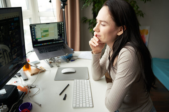 Thoughtful Woman Working On Laptop At Desk