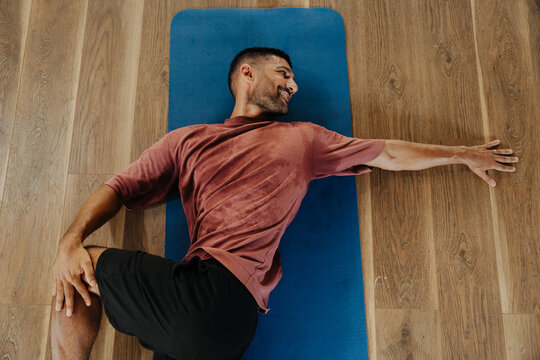 Man Stretches on Yoga Mat in a Fitness Studio During the Day